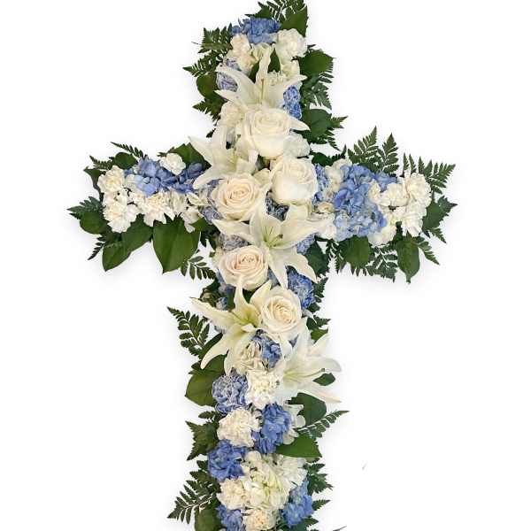Cross-shaped floral arrangement with white lilies, roses, and blue hydrangeas