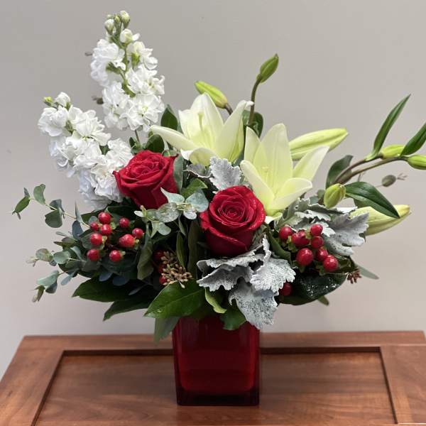 Red roses and white lilies arranged in a red glass vase