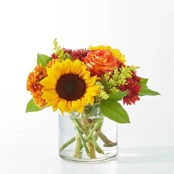 Sunflower and mixed autumn flowers in a clear glass vase