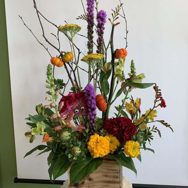 Tall mixed floral arrangement in a wooden box with orange accents