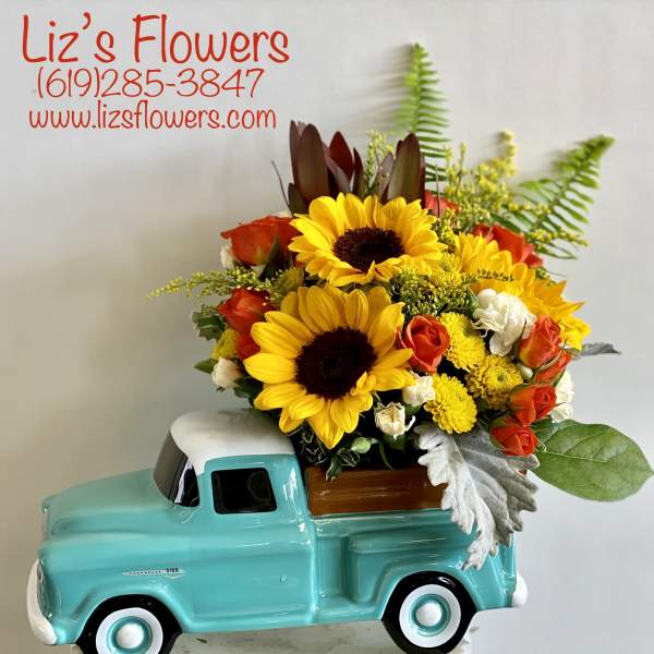 Sunflower and rose arrangement in a turquoise truck planter