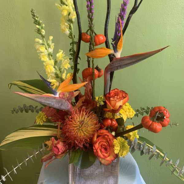 Tropical floral arrangement with orange roses and bird-of-paradise blooms