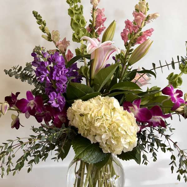 Tall mixed bouquet with hydrangea, lilies, orchids, and snapdragons in a glass vase
