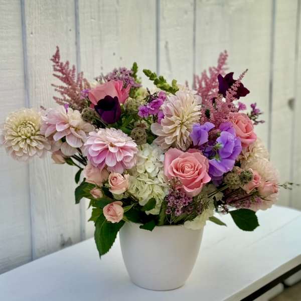 Pink and purple mixed flower arrangement in a white vase