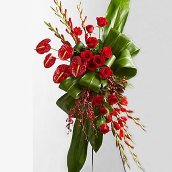 Red roses and anthuriums with tall green leaves in a modern arrangement
