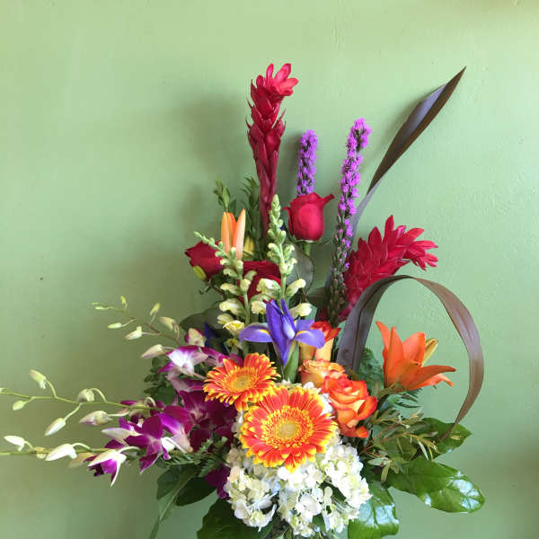 Colorful mixed bouquet in a glass vase with lilies, roses, and orchids