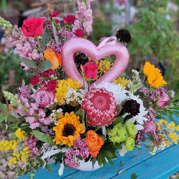 Mixed bouquet with roses, sunflowers, and a pink heart pick