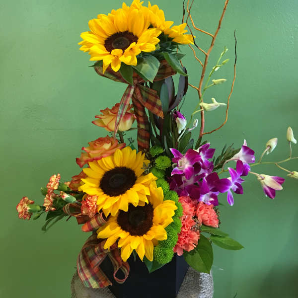 Tall mixed bouquet with sunflowers, orchids, and roses in a black container