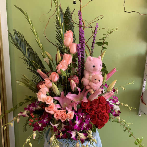 Large pink and red floral arrangement with two teddy bears