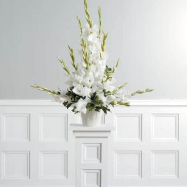 White floral arrangement in a ribbed vase on a pedestal