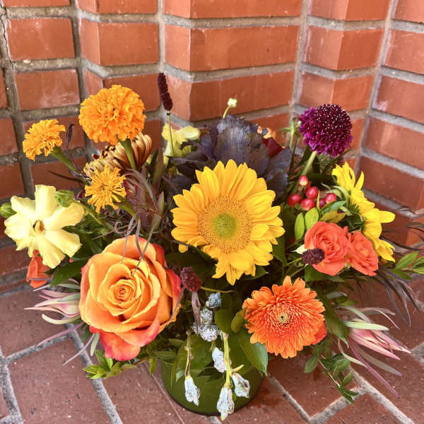 Mixed bouquet with sunflowers, roses, and chrysanthemums in a green vase