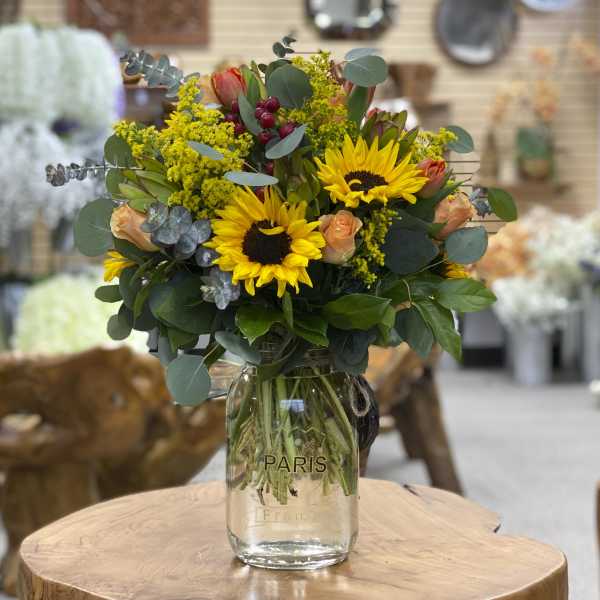 Sunflower and peach rose bouquet in a clear glass vase