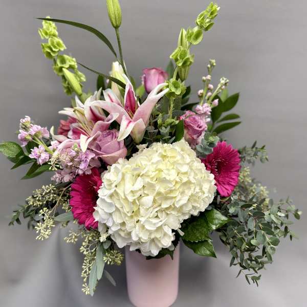 Tall pink and white mixed flower arrangement with hydrangea, lilies, and gerbera daisies in a pink vase