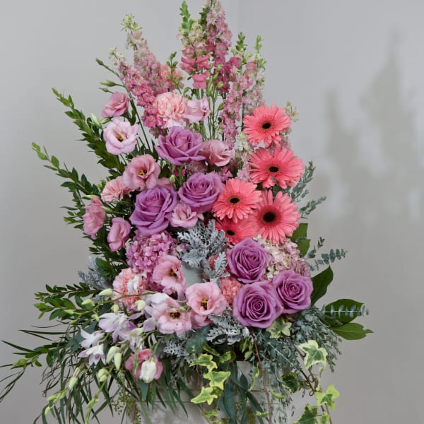 Tall pink and purple floral arrangement with roses and gerbera daisies