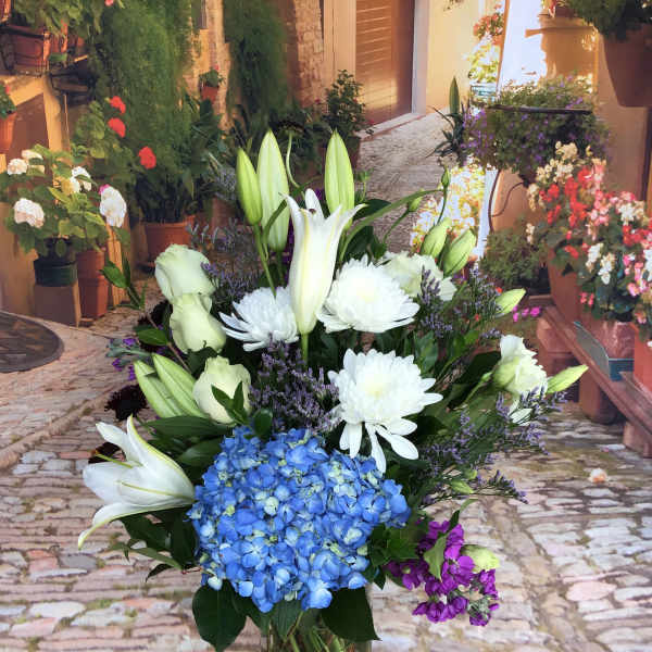Bouquet of white lilies, blue hydrangea, and white chrysanthemums in a glass vase