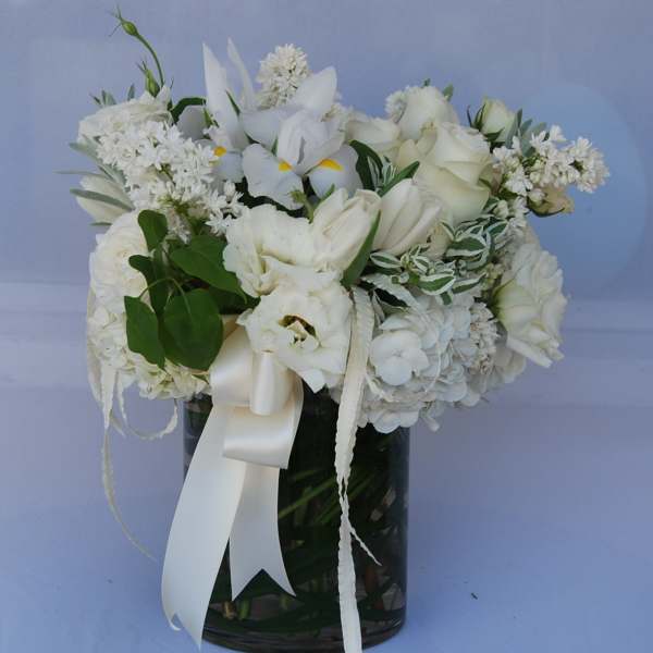 White floral arrangement in a dark glass vase with a satin ribbon