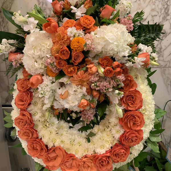 Large circular floral wreath with orange and white flowers on an easel