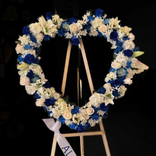 Heart-shaped floral wreath with blue and white flowers on an easel
