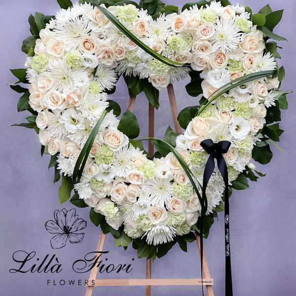 Heart-shaped floral wreath of white and blush flowers on an easel