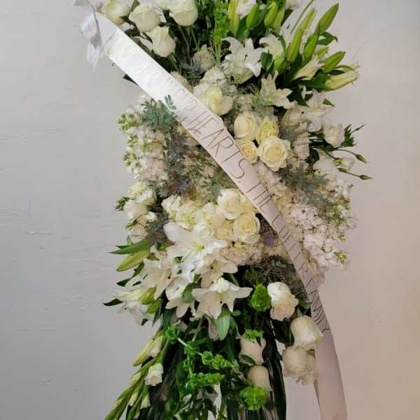 Tall white floral standing spray on an easel with a ribbon sash