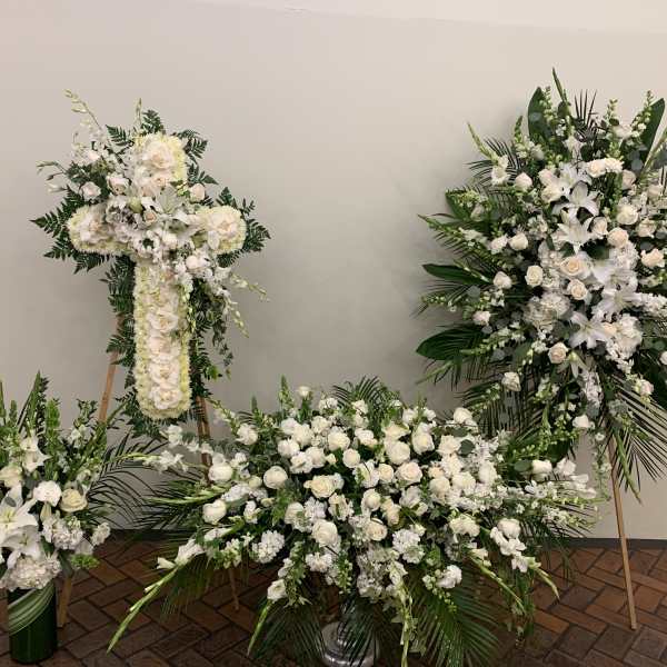 Four white floral funeral arrangements with lilies and roses