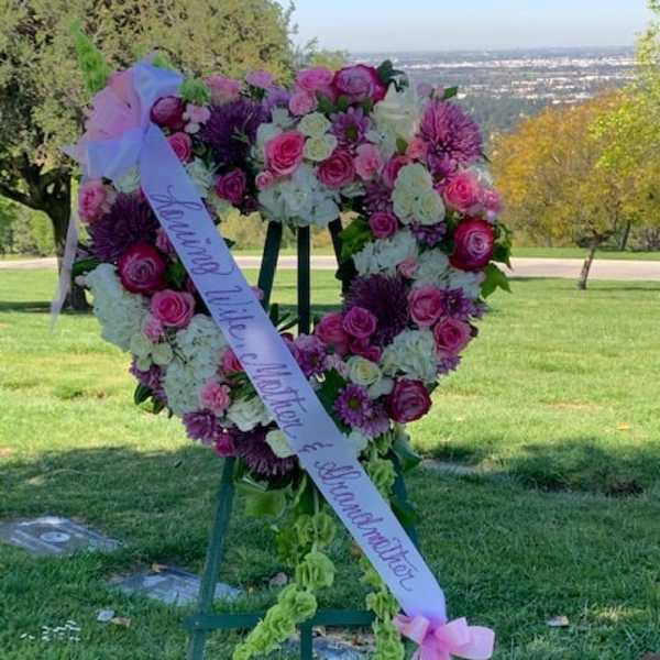 Heart-shaped floral wreath on an easel with a pink ribbon