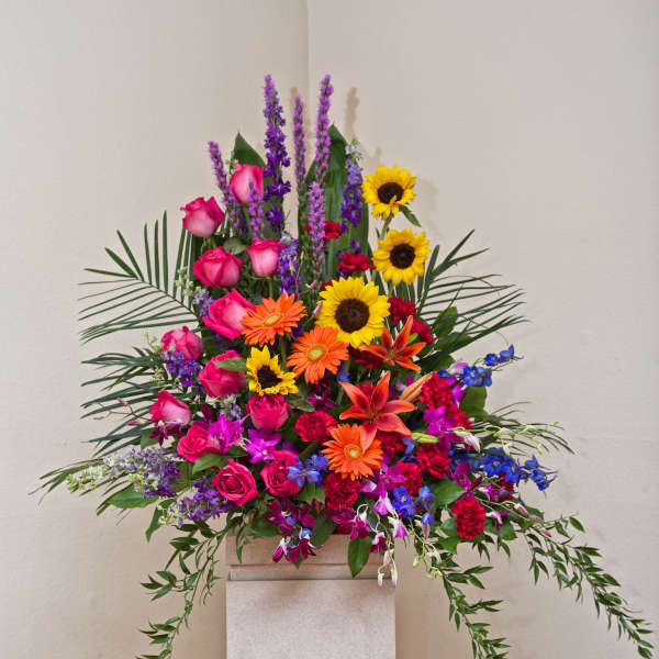 Tall colorful floral arrangement with roses, sunflowers, orchids, and lilies