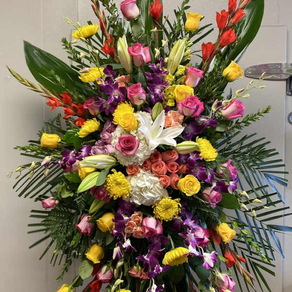Large standing floral spray with roses, lilies, orchids, and yellow blooms