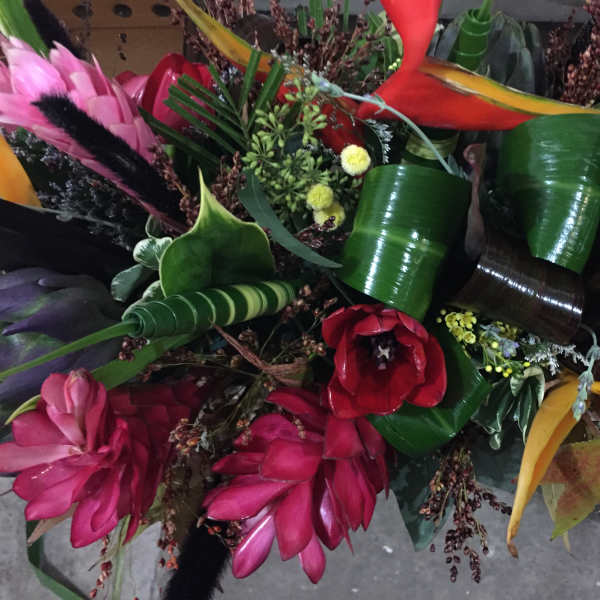 Tropical bouquet with red, pink, and yellow flowers and glossy green leaves