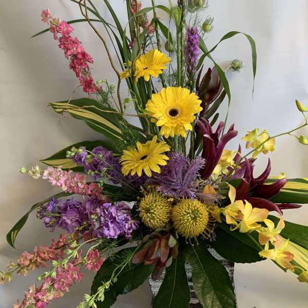 Tall mixed bouquet with yellow gerberas, purple blooms, and pink flowers