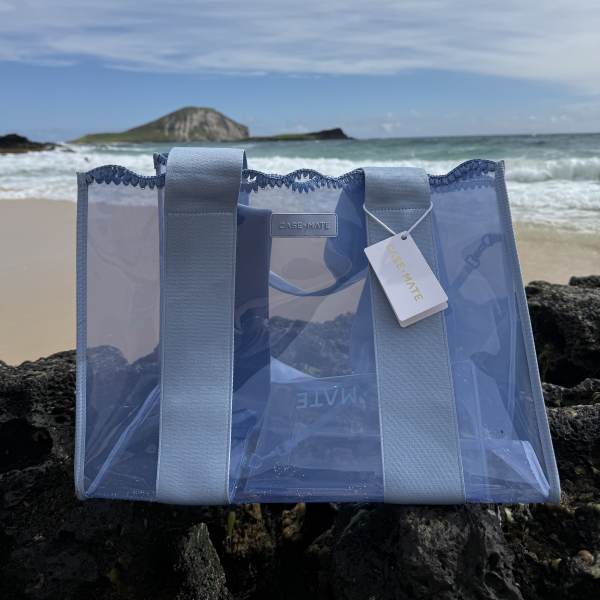 Translucent blue crochet tote with wide light-blue straps, clear body and branded hanging tag.