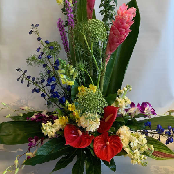 Tall tropical arrangement with pink ginger, red anthuriums, and purple orchids