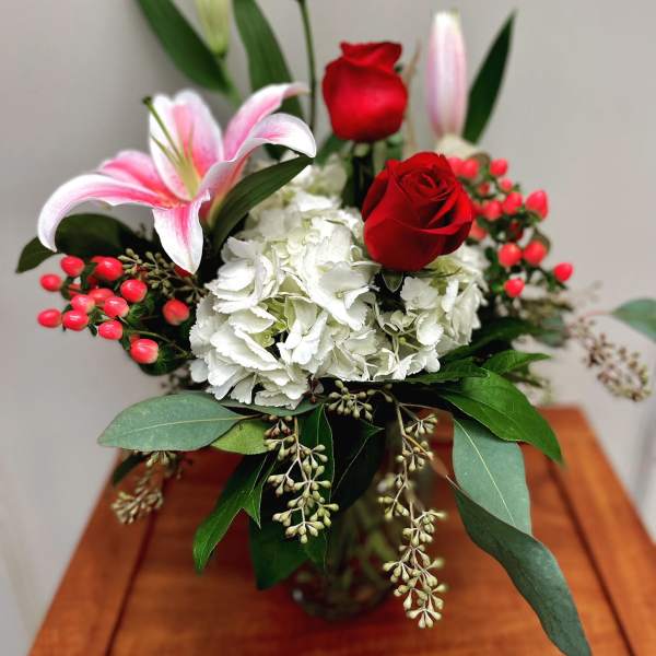 Bouquet of red roses, white hydrangea, and pink lilies in a vase