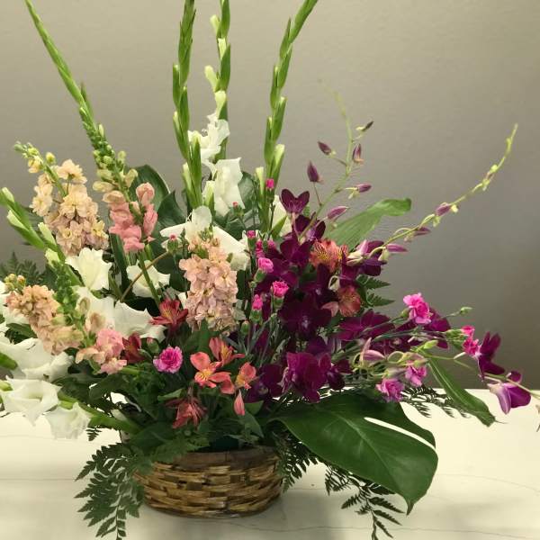 Mixed floral arrangement in a woven basket with white, pink, and purple blooms