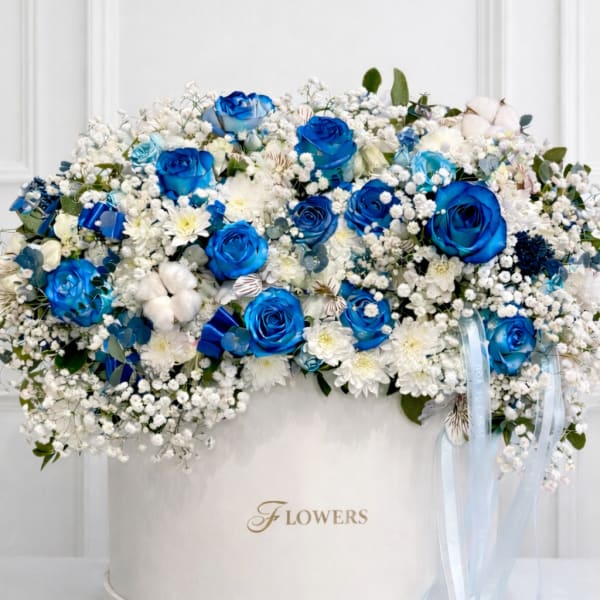 Blue and white rose arrangement in a round white box with ribbon
