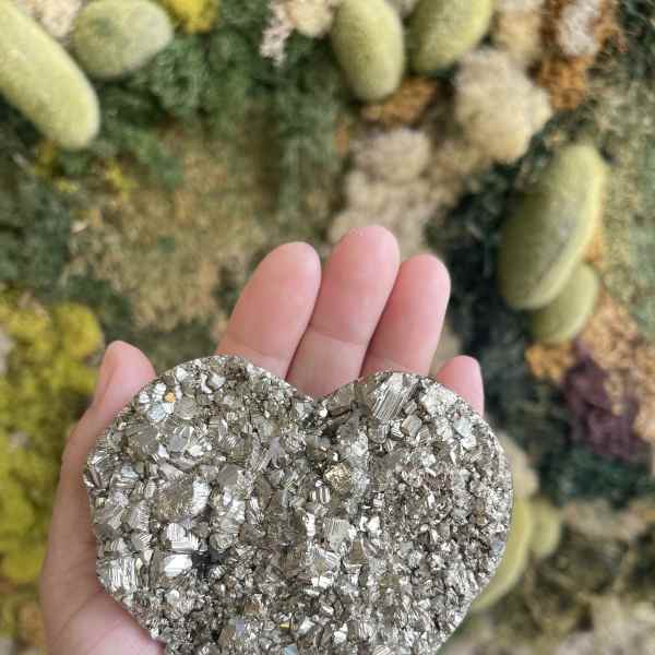 Hand holding a metallic heart-shaped crystal cluster