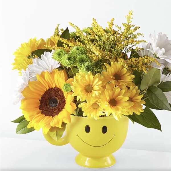 Yellow smiley-face mug filled with sunflowers and white daisies