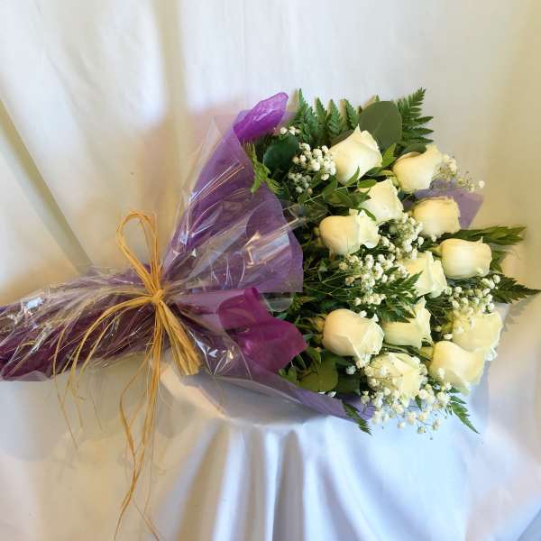 Bouquet of white roses wrapped in purple paper