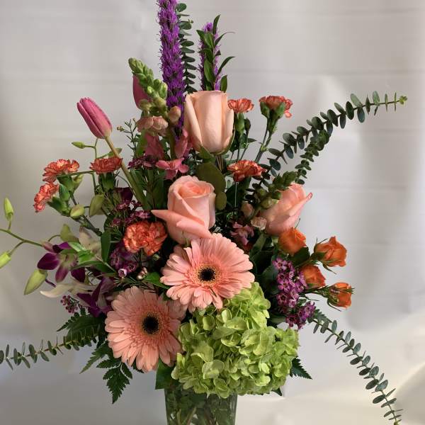 Mixed bouquet in a clear glass vase with pink roses, gerberas, and green hydrangea