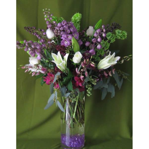 Purple and white floral arrangement in a clear glass vase