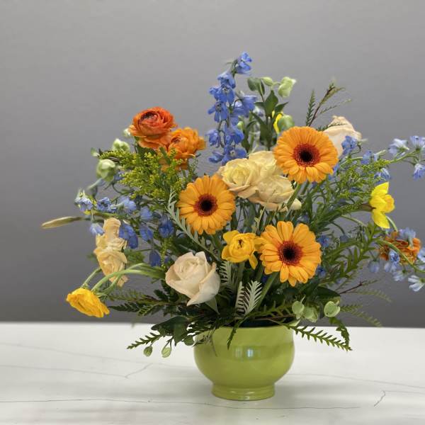 Mixed bouquet in a green vase with orange and blue flowers