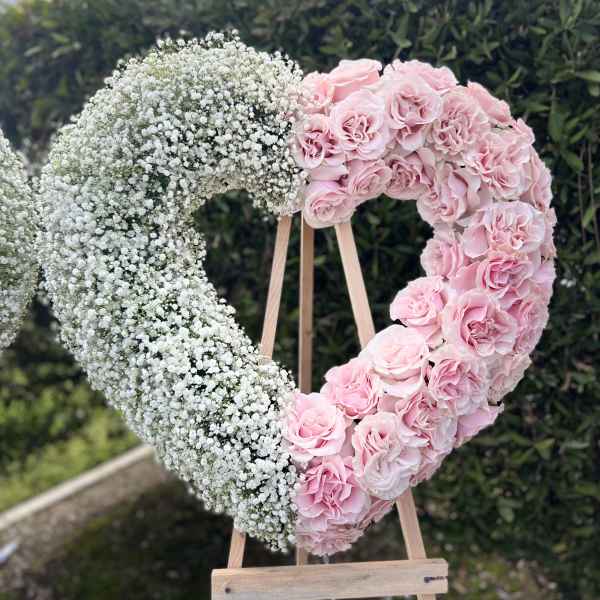 Heart-shaped floral display with pink roses and white baby's breath on an easel