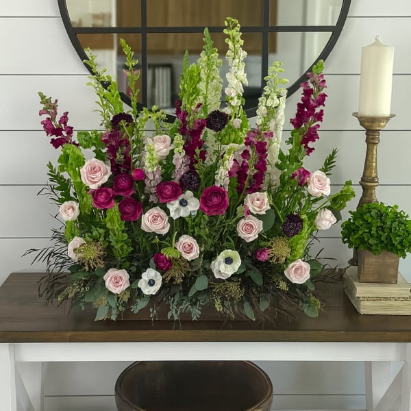 Tall floral arrangement with pink roses and magenta snapdragons in a low container