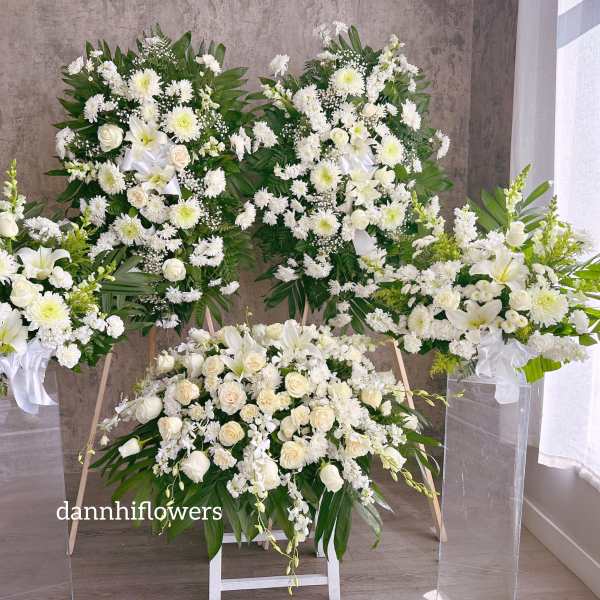 White floral funeral sprays and a casket spray with lilies and roses