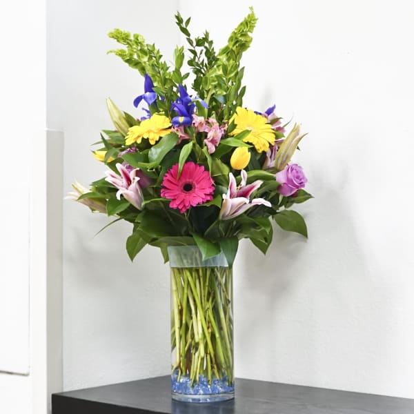Tall mixed bouquet in a clear glass vase with bright flowers