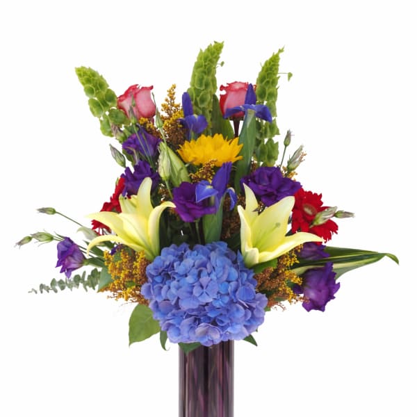 Colorful mixed bouquet in a tall purple glass vase
