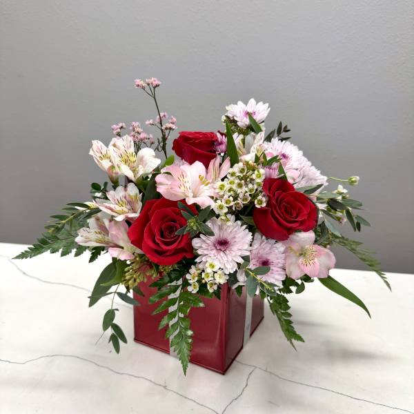 Bouquet of red roses and pink mixed flowers in a red box