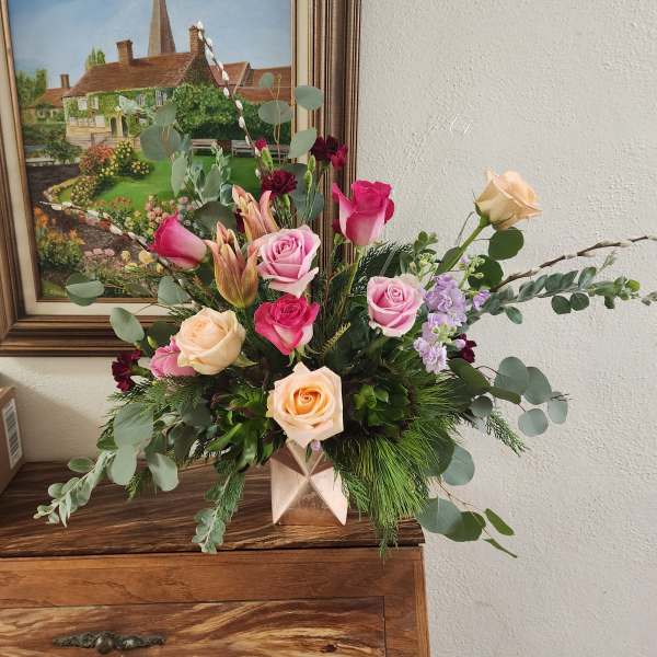 Mixed bouquet of pink and peach roses in a geometric vase