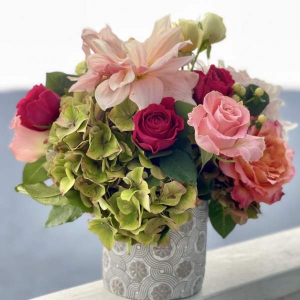 Pink and peach roses with green hydrangeas in a patterned vase