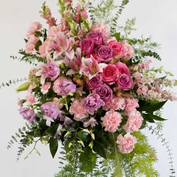 Large pink and lavender floral arrangement with cascading greenery